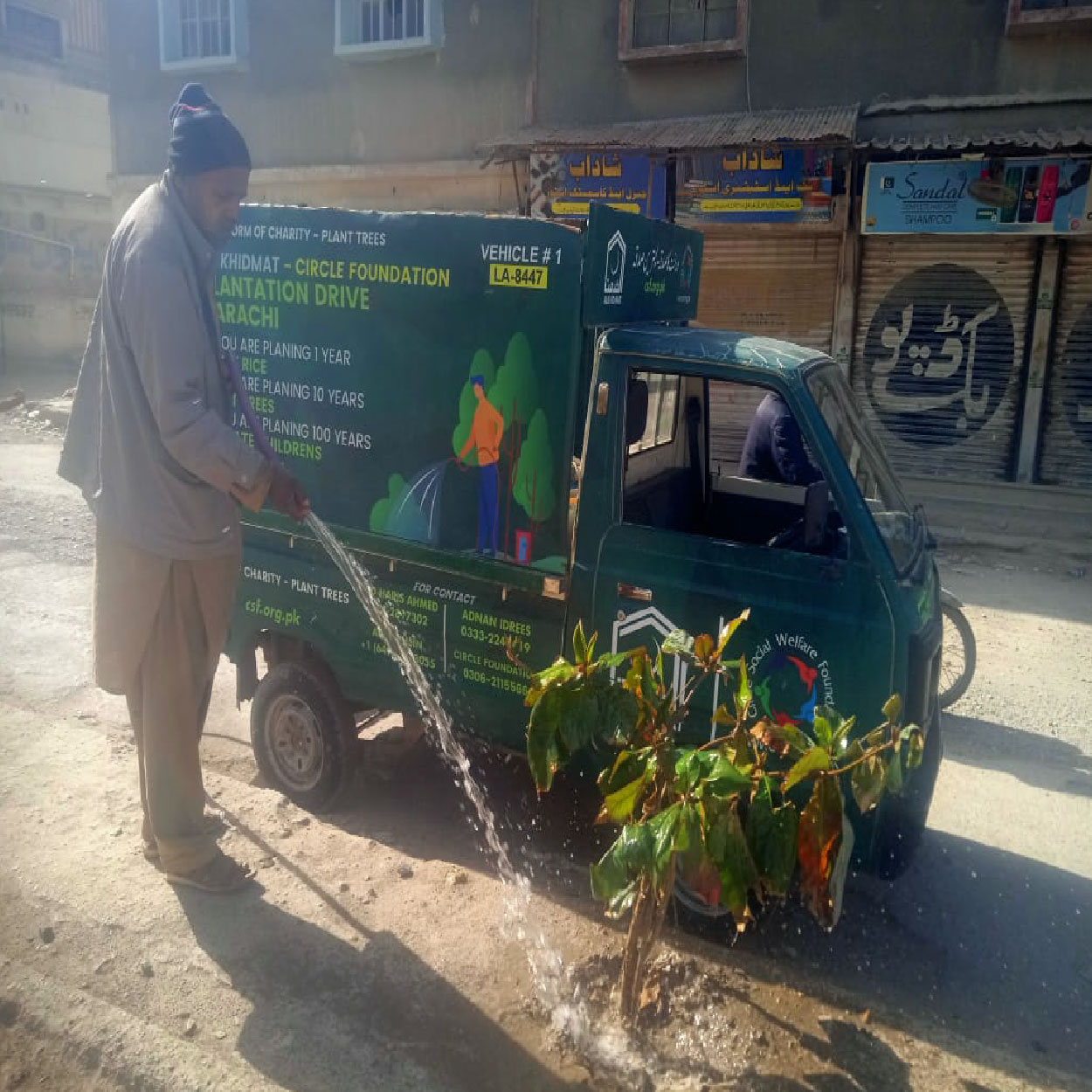 CSF plantation drive volunteer watering young tree next to Circle Social Welfare Foundation branded vehicle in environmental sustainability activity