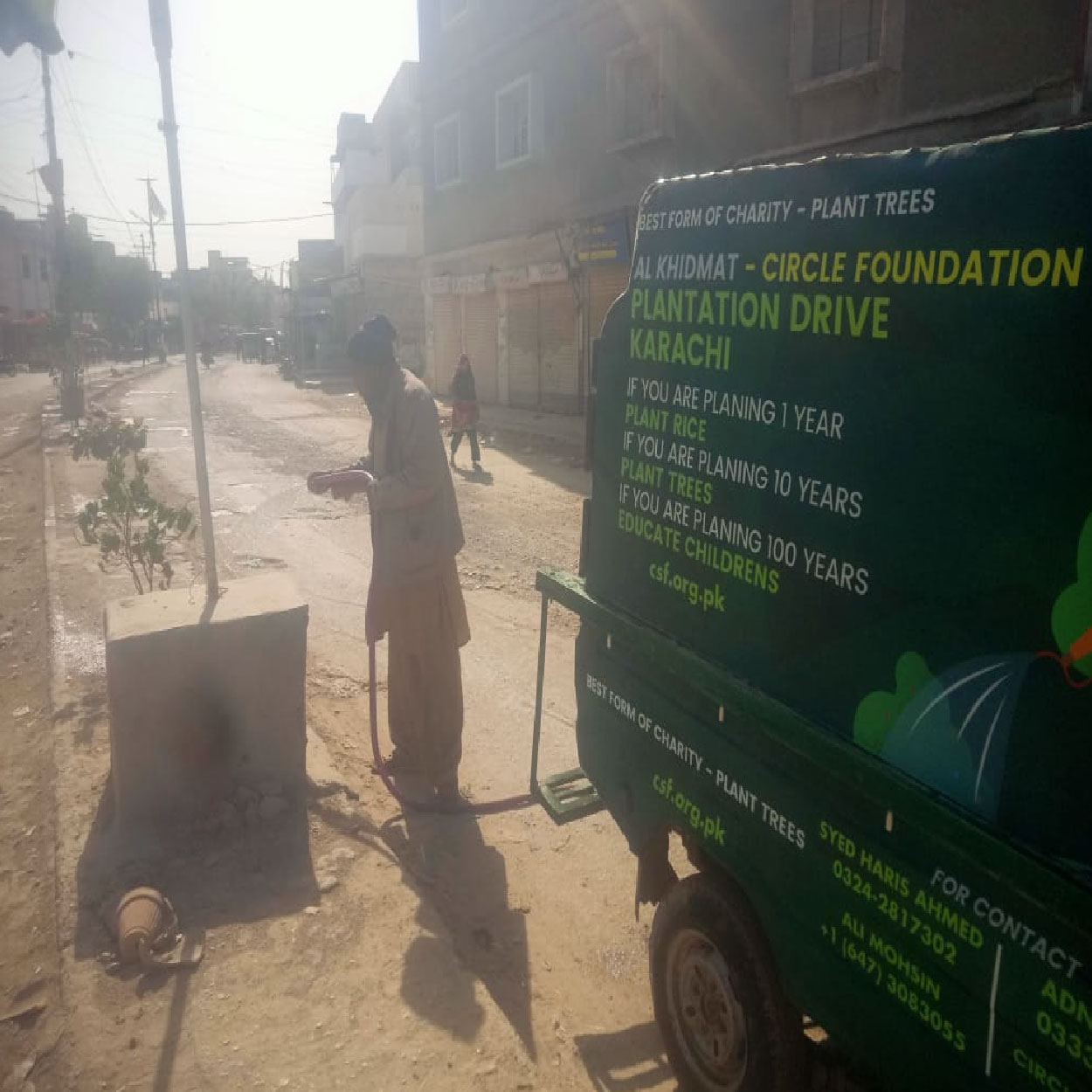 CSF plantation drive volunteer watering a young tree beside a Circle Social Welfare Foundation branded vehicle on a city street in Karachi