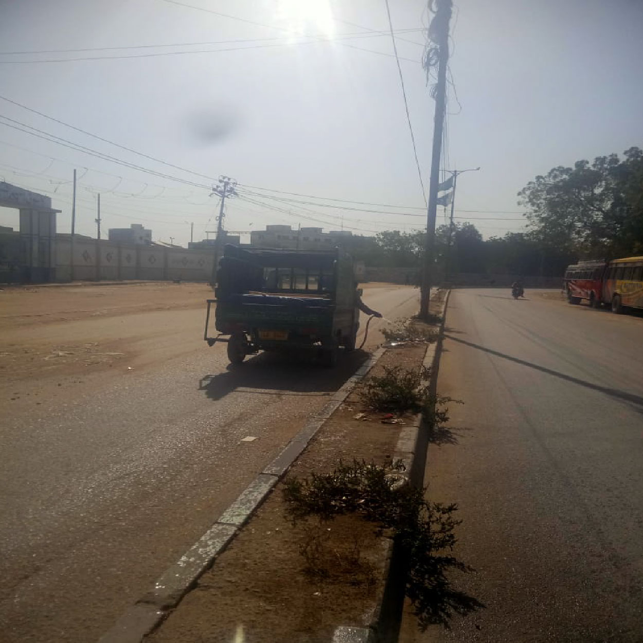 small passenger rickshaw on city road in Karachi with buses and urban street view for community outreach documentation by CSF